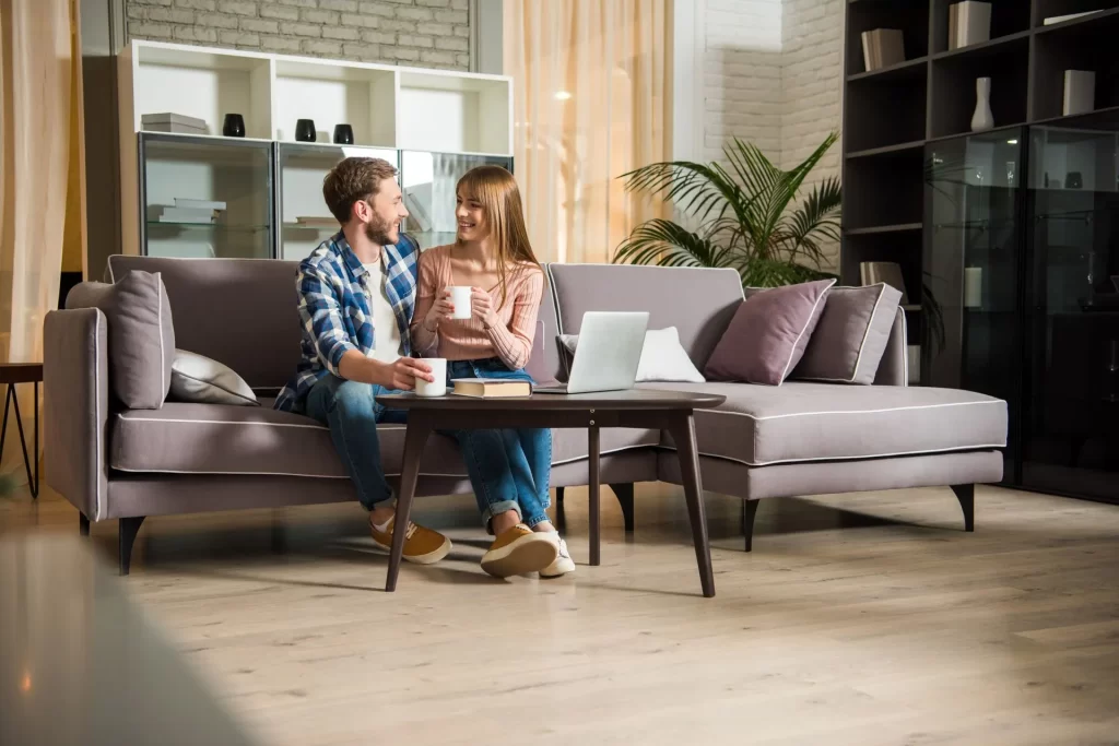 Man and woman sitting on couch drinking coffee